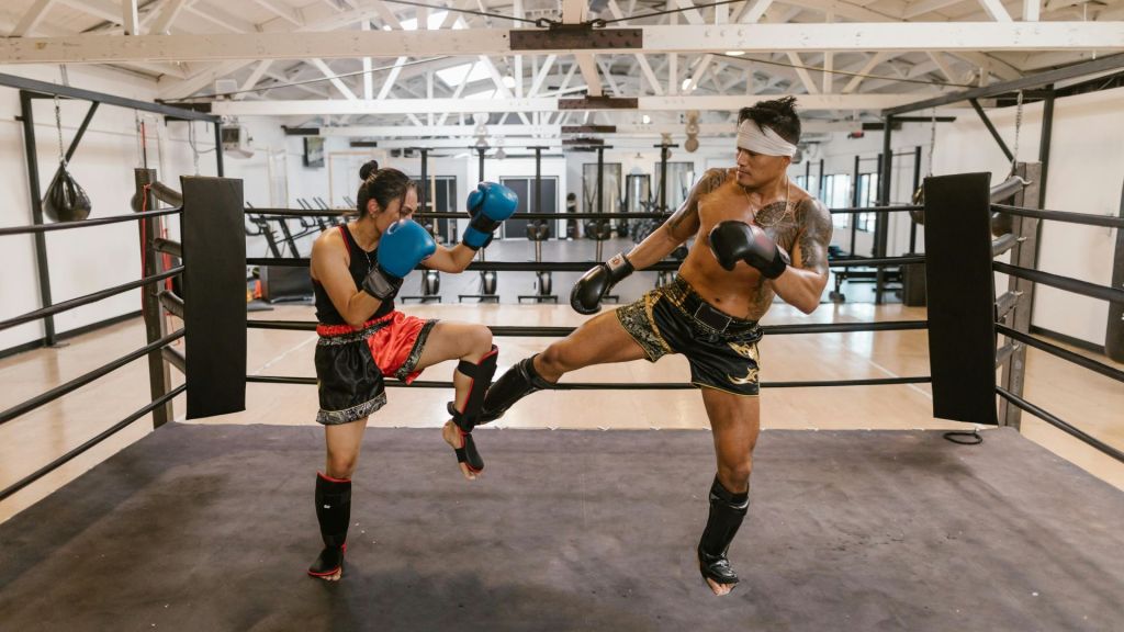 A man and a woman sparring Muay Thai in a boxing ring